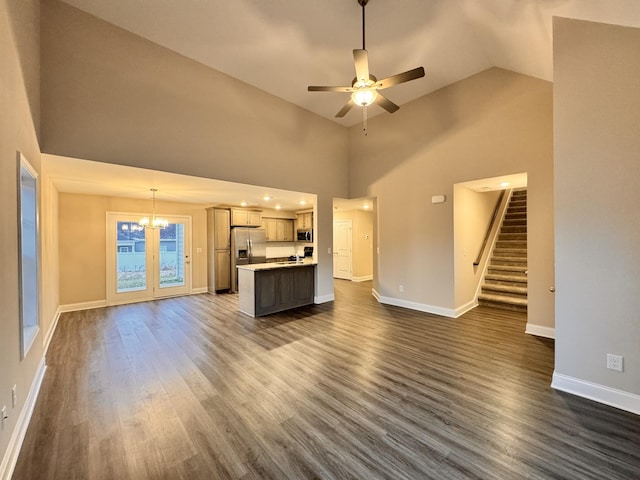 unfurnished living room with dark hardwood / wood-style flooring, high vaulted ceiling, and ceiling fan with notable chandelier