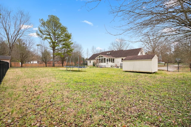 view of yard featuring a trampoline, an outbuilding, a fenced backyard, and a storage unit