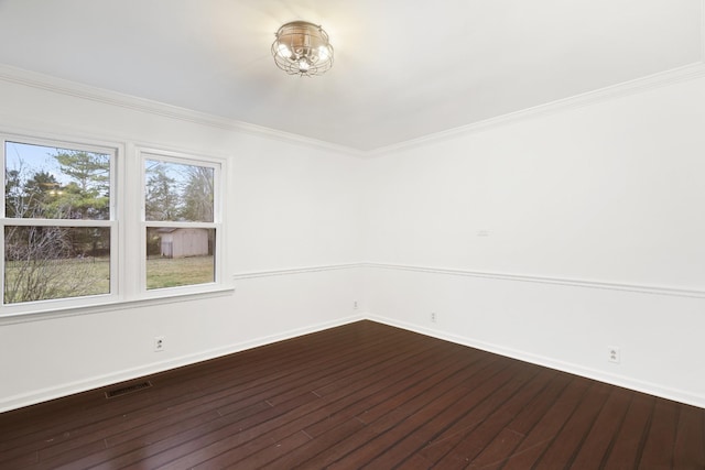 spare room with dark wood-style floors, baseboards, visible vents, and crown molding