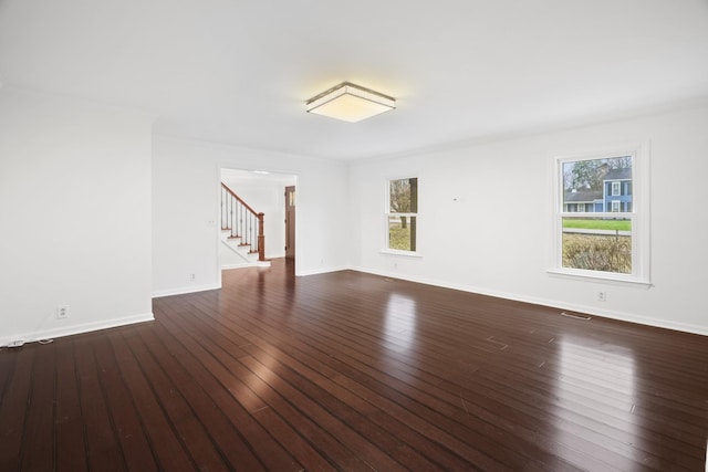 empty room featuring stairway, dark wood-style flooring, visible vents, and baseboards