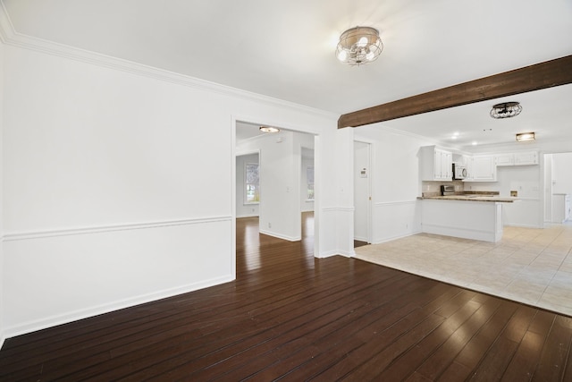 unfurnished living room featuring baseboards, light wood finished floors, and crown molding