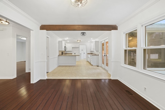 unfurnished living room with baseboards, light wood finished floors, and crown molding