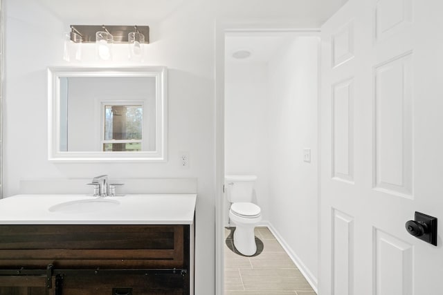 bathroom with toilet, baseboards, and vanity