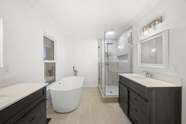 bathroom featuring a soaking tub, a stall shower, two vanities, and a sink