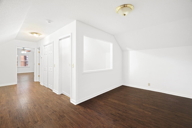 bonus room with dark wood-type flooring, vaulted ceiling, and baseboards