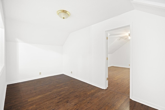 spare room with lofted ceiling, dark wood-style floors, and baseboards