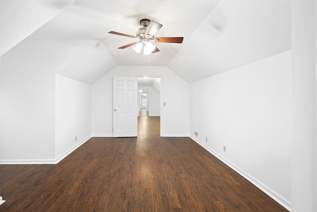 additional living space featuring dark wood-style floors, vaulted ceiling, baseboards, and ceiling fan