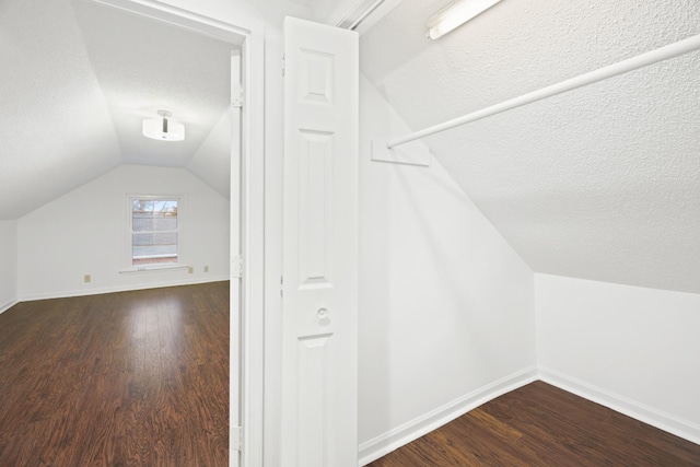 additional living space with lofted ceiling, baseboards, dark wood finished floors, and a textured ceiling