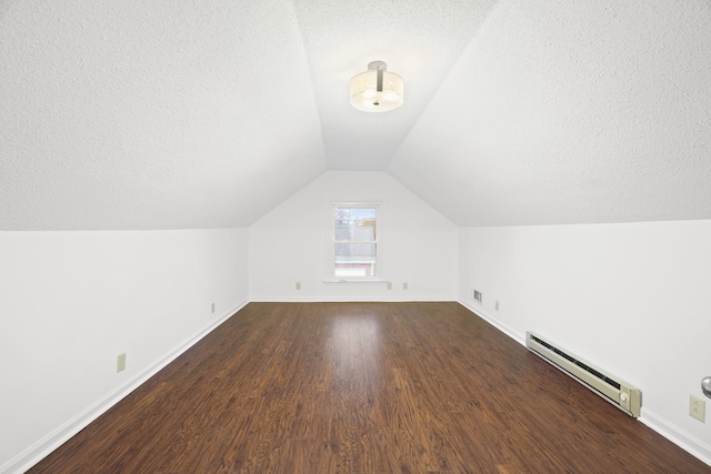 additional living space featuring a textured ceiling, dark wood-style flooring, baseboards, vaulted ceiling, and baseboard heating