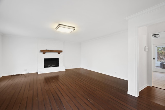 unfurnished living room featuring wood-type flooring, a fireplace, ornamental molding, and baseboards