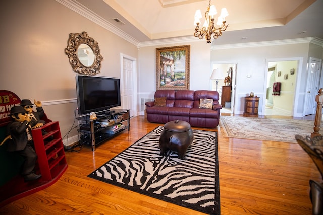 living room featuring an inviting chandelier, wood-type flooring, crown molding, and a tray ceiling