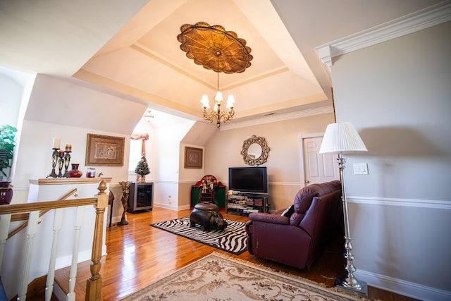 living room featuring hardwood / wood-style floors, a tray ceiling, an inviting chandelier, and ornamental molding