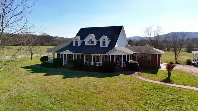 view of front of house featuring a mountain view, covered porch, and a front yard