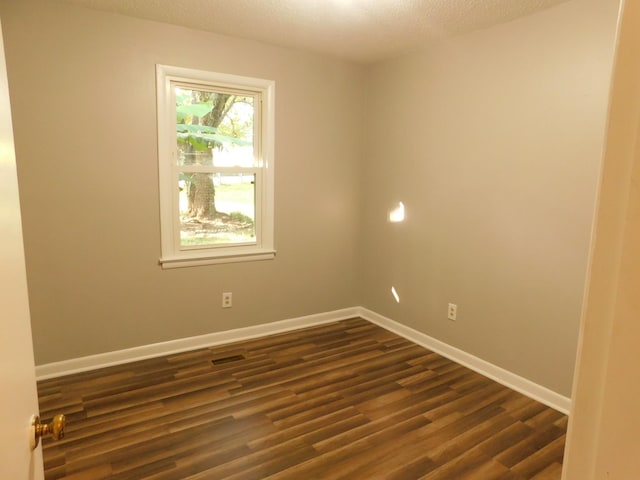 spare room with a textured ceiling and dark hardwood / wood-style floors