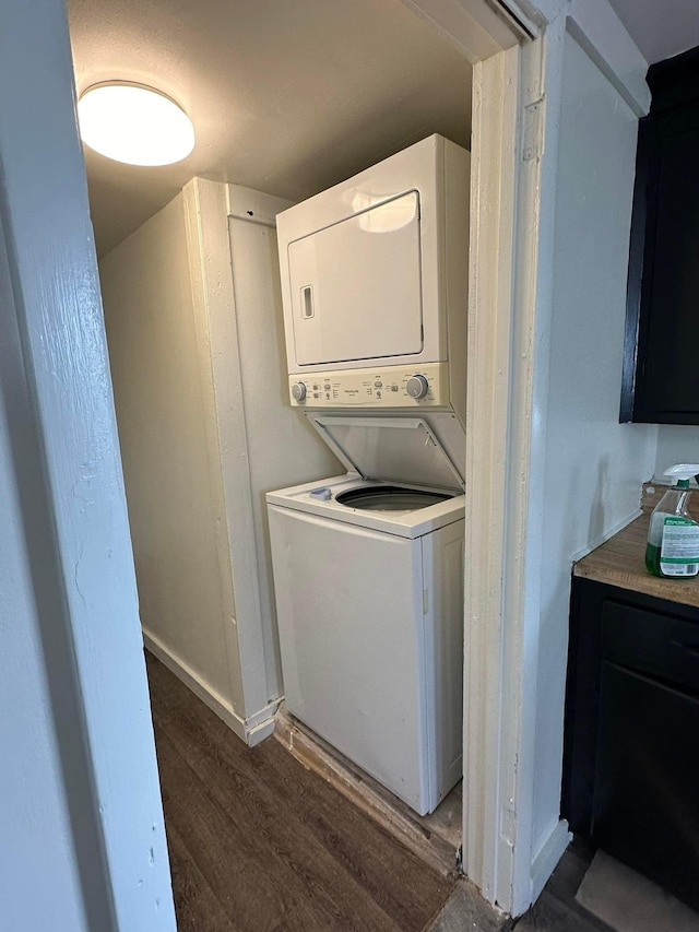 laundry room with stacked washer / dryer and dark wood-type flooring