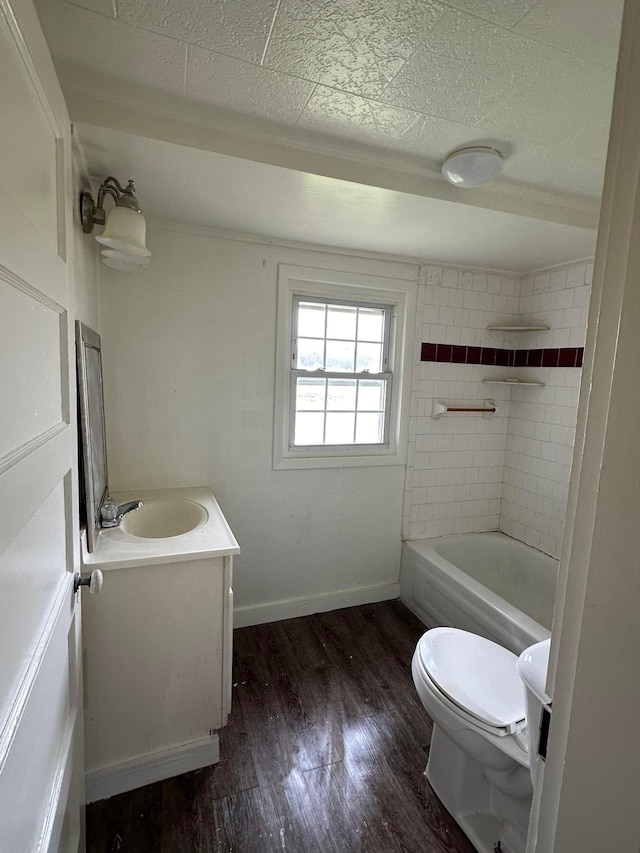 full bathroom with wood-type flooring, a textured ceiling, toilet, vanity, and tiled shower / bath