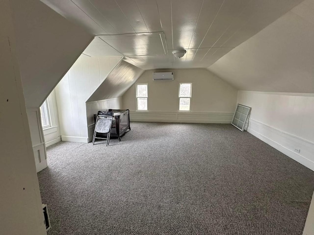 additional living space with carpet, vaulted ceiling, and a wall unit AC