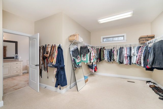 walk in closet with light carpet