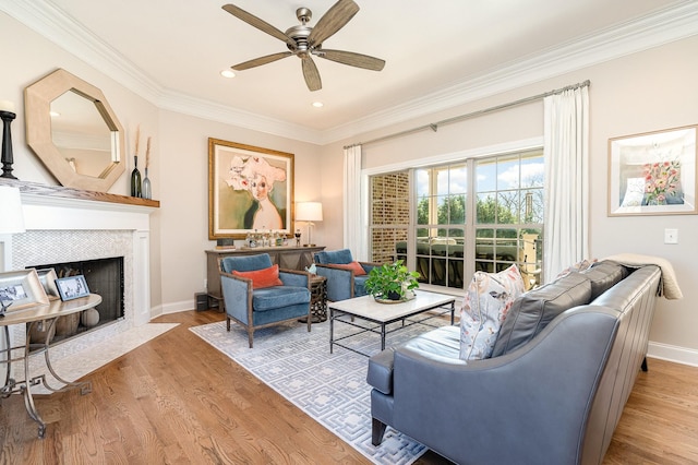 living room featuring ceiling fan, crown molding, light wood-type flooring, and a fireplace