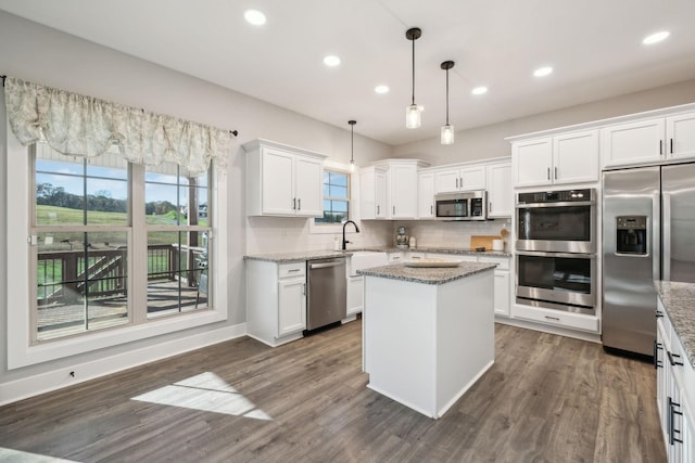 kitchen with white cabinetry, light stone countertops, sink, pendant lighting, and appliances with stainless steel finishes