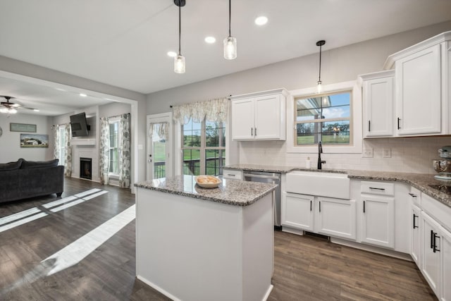 kitchen featuring ceiling fan, sink, pendant lighting, white cabinets, and a kitchen island