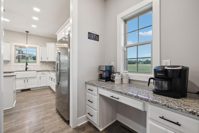 kitchen with white cabinetry, sink, backsplash, stainless steel fridge, and decorative light fixtures