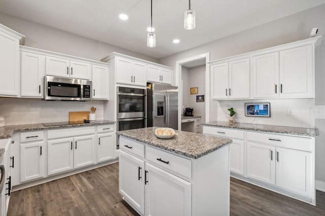 kitchen featuring white cabinets, decorative backsplash, appliances with stainless steel finishes, a kitchen island, and light stone counters