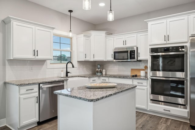 kitchen featuring sink, a center island, hanging light fixtures, white cabinets, and appliances with stainless steel finishes