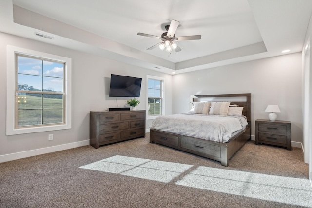 carpeted bedroom with a tray ceiling and ceiling fan