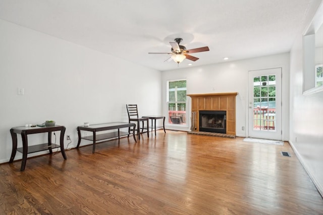 living room featuring plenty of natural light, ceiling fan, dark wood-type flooring, and a tile fireplace