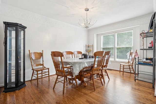 dining space with a chandelier, wood-type flooring, and crown molding