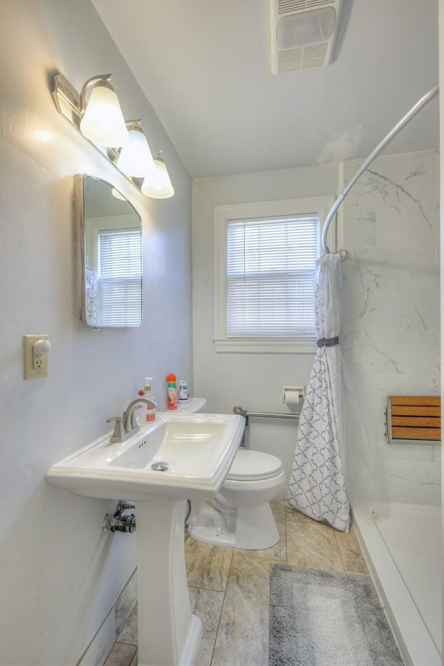 bathroom with a shower, tile patterned floors, toilet, and plenty of natural light