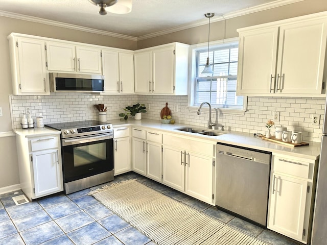 kitchen featuring sink, backsplash, pendant lighting, white cabinets, and appliances with stainless steel finishes