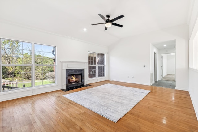 unfurnished living room featuring ceiling fan, a healthy amount of sunlight, vaulted ceiling, and light wood-type flooring