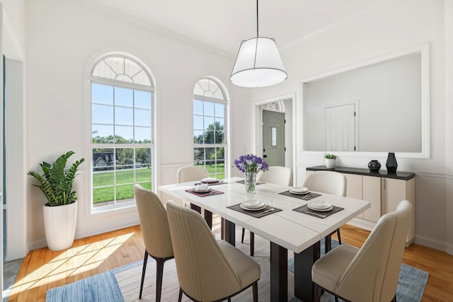 dining area with a healthy amount of sunlight, light hardwood / wood-style floors, and ornamental molding