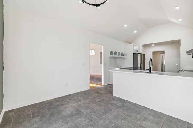 kitchen featuring white cabinets, stainless steel fridge, vaulted ceiling, and sink