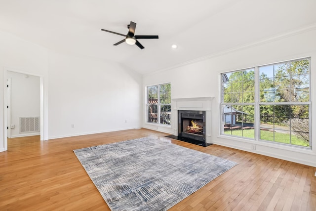 living room with ceiling fan, a healthy amount of sunlight, light wood-type flooring, and vaulted ceiling