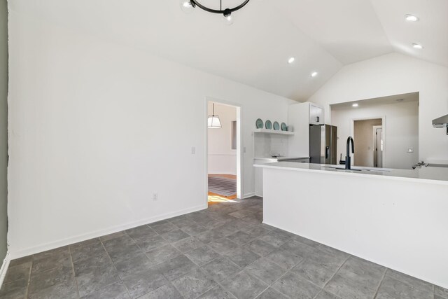 kitchen featuring white cabinets, stainless steel fridge with ice dispenser, sink, and vaulted ceiling