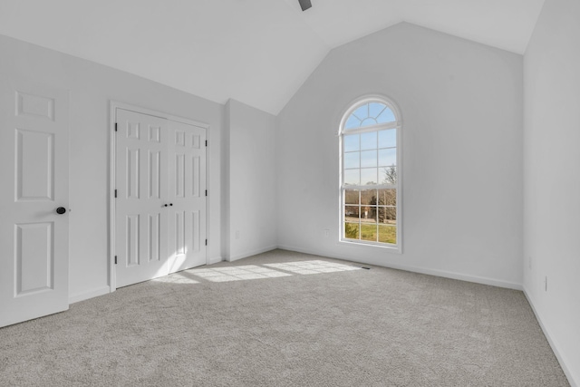 unfurnished bedroom featuring multiple windows, light carpet, and lofted ceiling