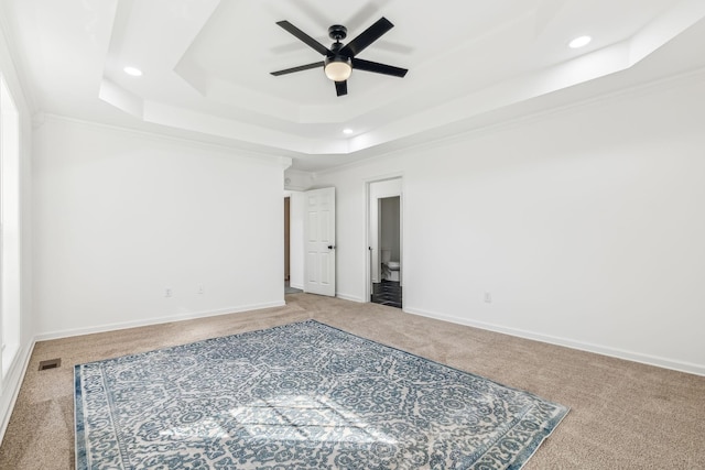 carpeted spare room with a raised ceiling, ceiling fan, and crown molding