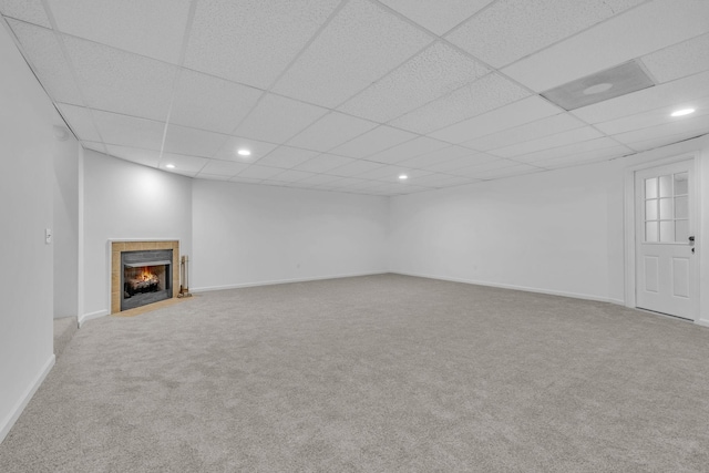 unfurnished living room featuring a fireplace, carpet flooring, and a drop ceiling