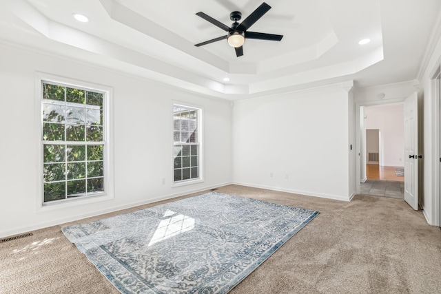 unfurnished room with carpet floors, a raised ceiling, ceiling fan, and crown molding