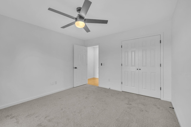 unfurnished bedroom with ceiling fan, light carpet, and a closet