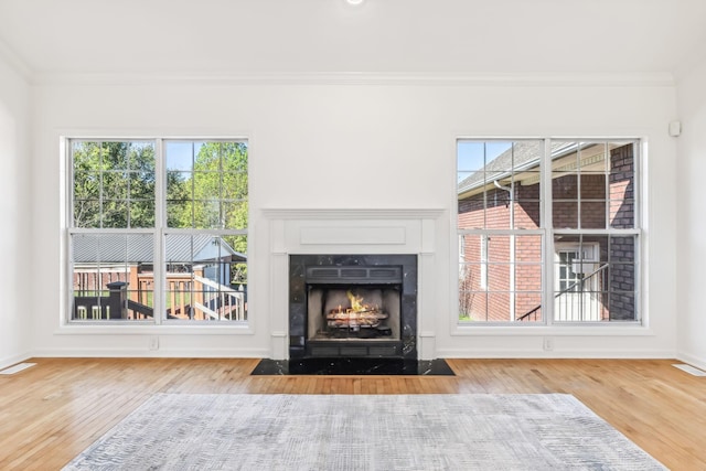 unfurnished living room with wood-type flooring, ornamental molding, and a high end fireplace