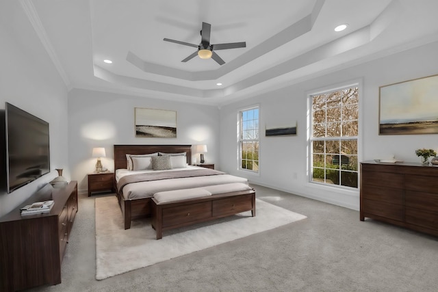 bedroom featuring ceiling fan, a raised ceiling, light colored carpet, and ornamental molding