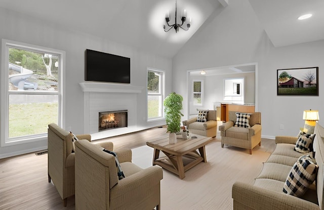 living room featuring a notable chandelier, plenty of natural light, high vaulted ceiling, and light hardwood / wood-style flooring