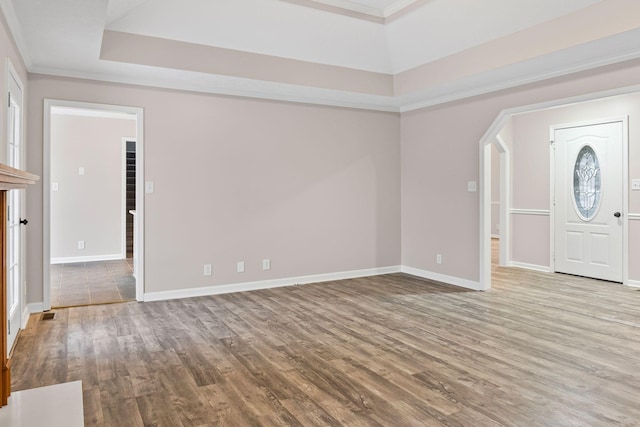 foyer entrance featuring a tray ceiling, light hardwood / wood-style floors, and ornamental molding