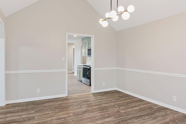 empty room with hardwood / wood-style flooring, a notable chandelier, and high vaulted ceiling