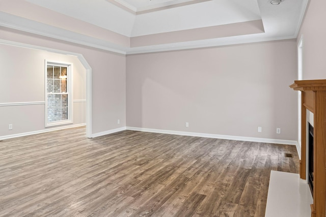 unfurnished living room featuring hardwood / wood-style floors, a raised ceiling, and crown molding