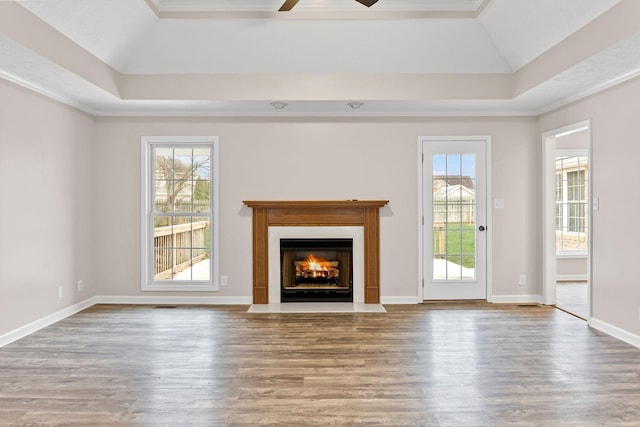 unfurnished living room with wood-type flooring, a raised ceiling, ceiling fan, and ornamental molding